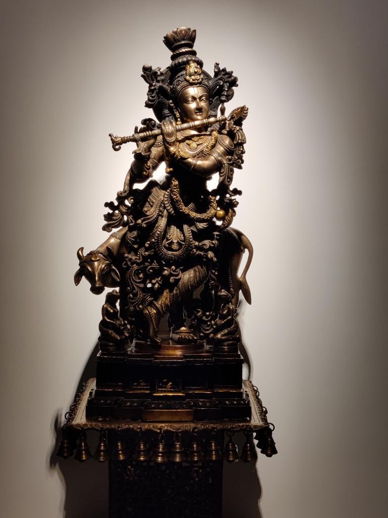 Bronze devotional sculpture illuminated against a plain wall
