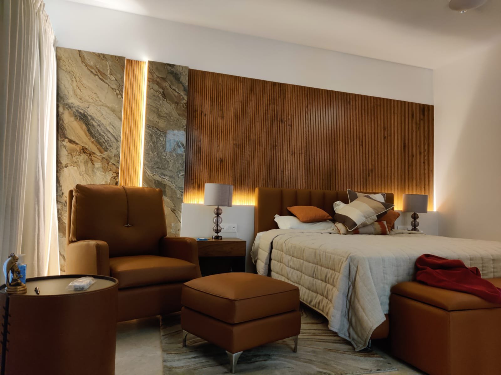 Residential bedroom with warm linear lighting behind a timber feature wall